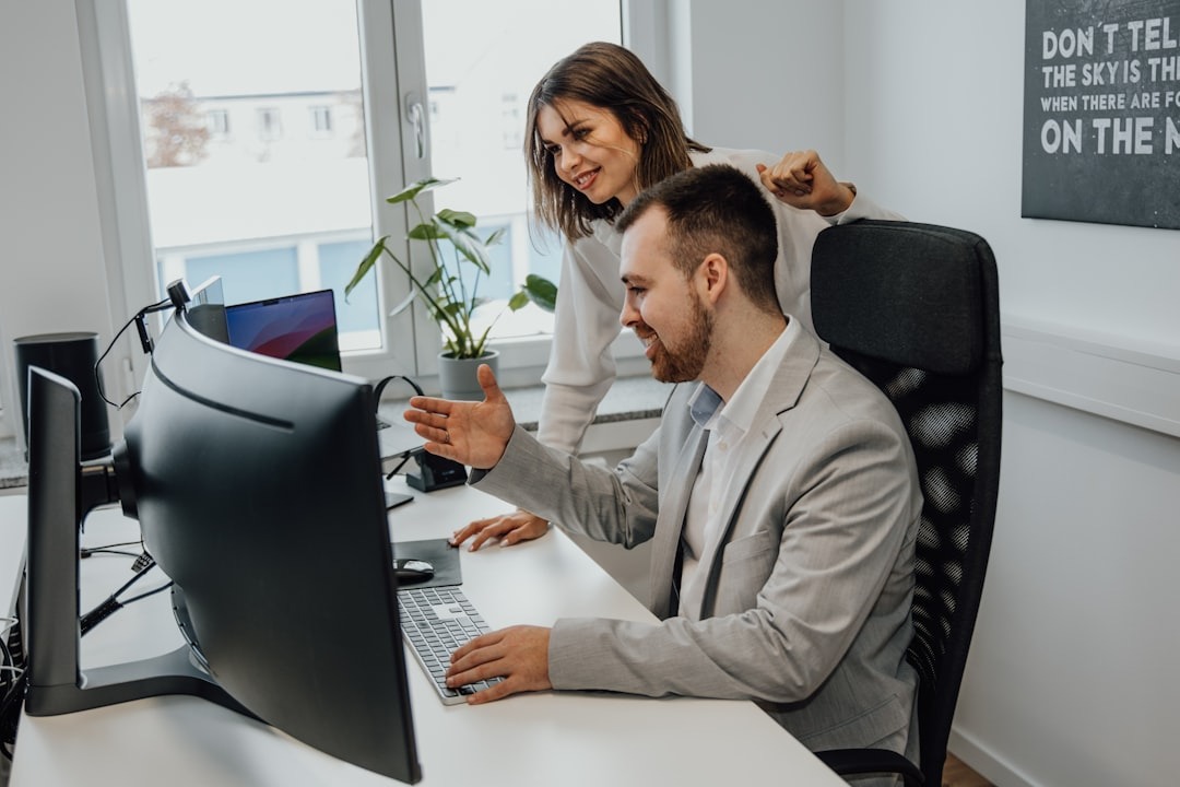 Two colleagues collaborate at a desk in a modern office.